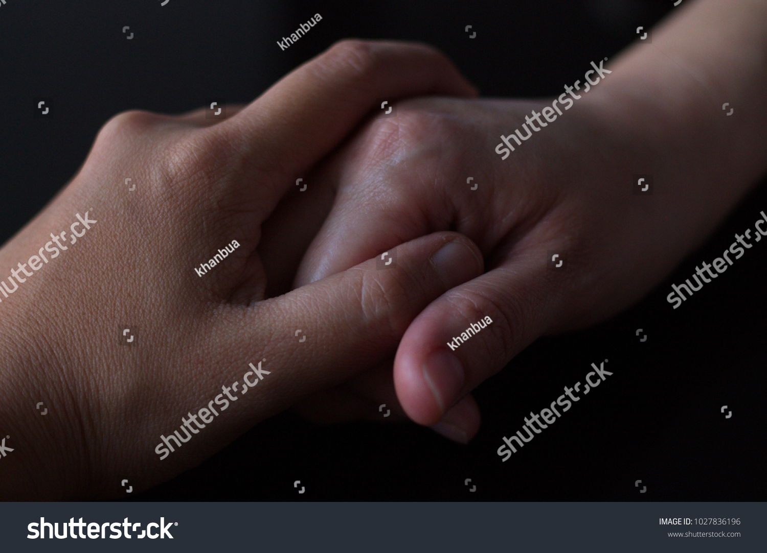 stock-photo-human-hands-holding-each-other-for-encouragement-over-the-black-background-1027836196